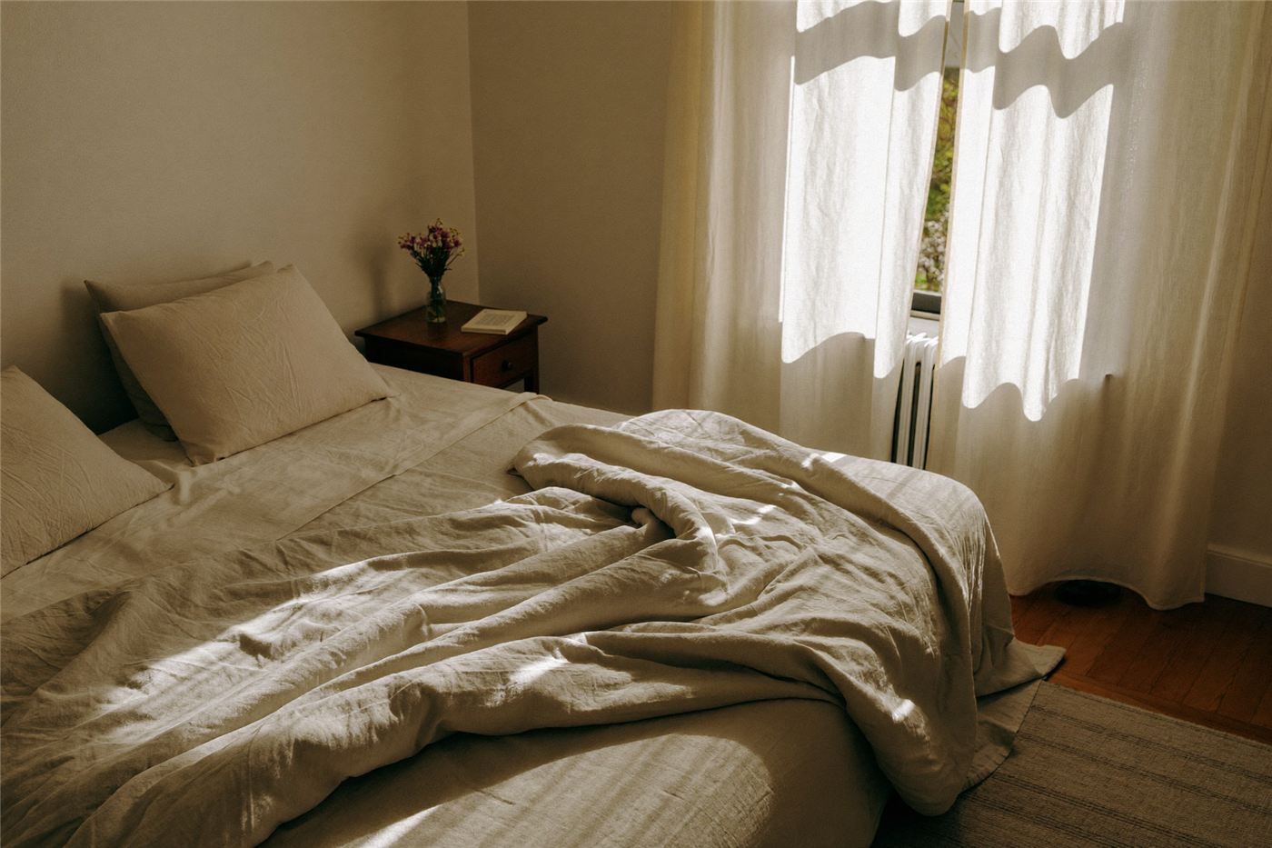 A calm bedroom with linen bedding in soft morning light