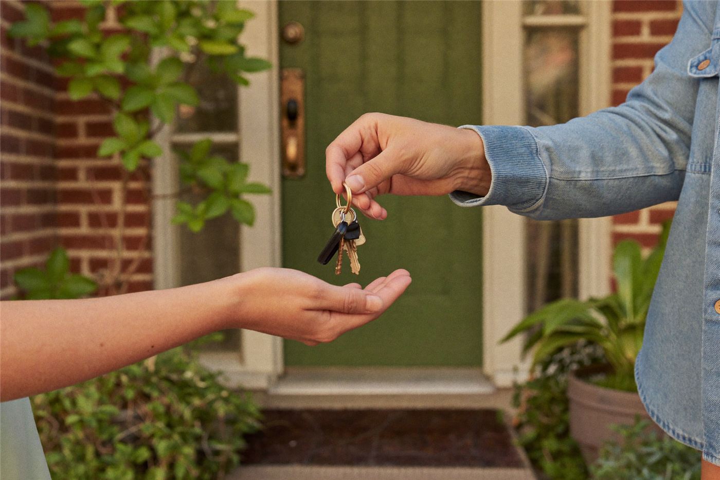 Hands warmly exchanging house keys on a doorstep