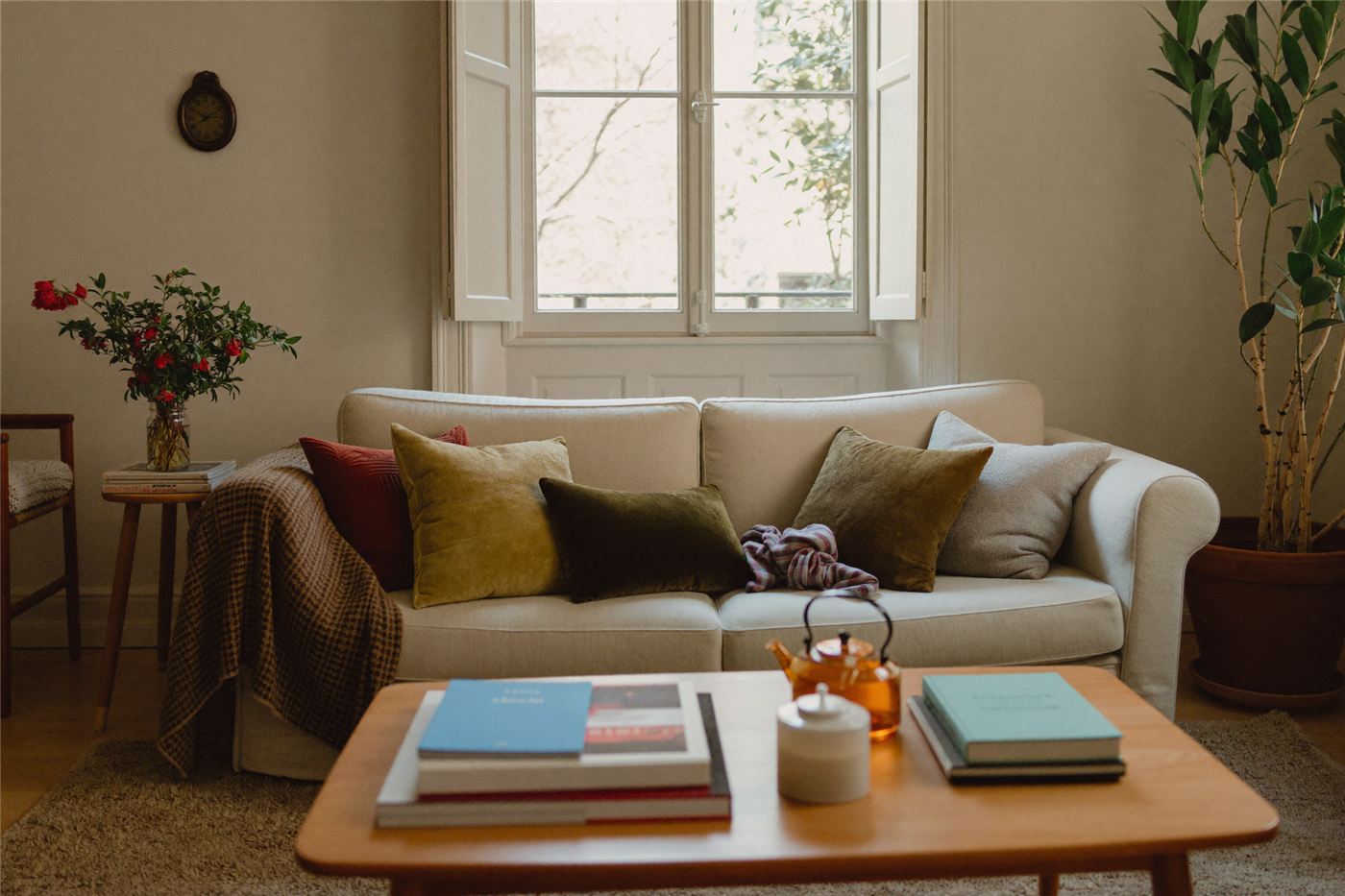 A warm living room with a cream linen sofa and green cushions